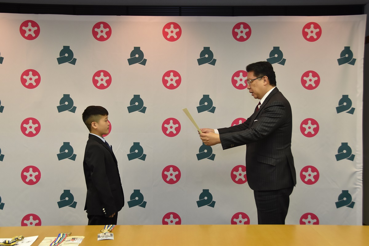 成澤区長が溝橋選手に表彰状を渡す最中